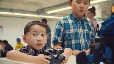 两个亚洲男孩兄弟站在一个人形机器人旁边微笑。 通过编程方法学习最新的机器人技术是